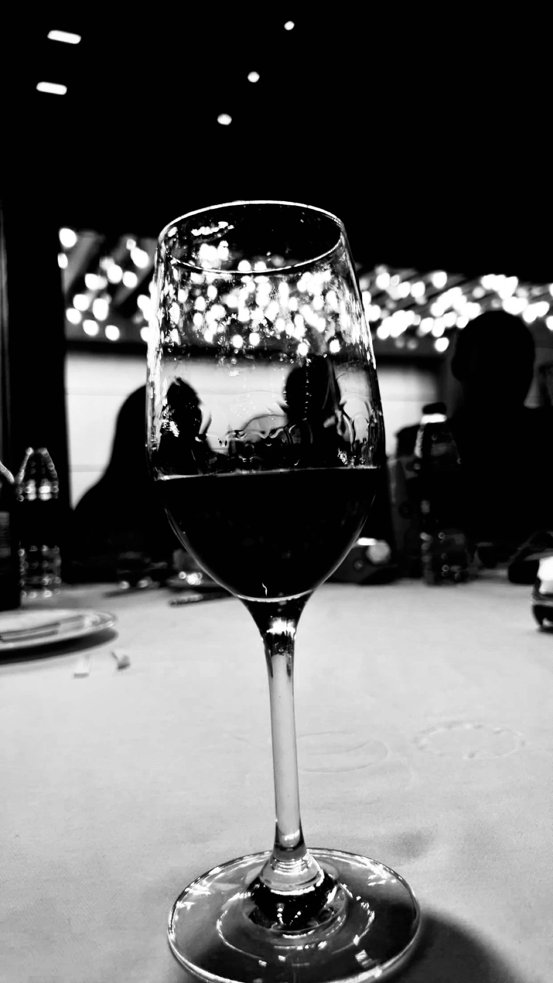 Glass of red wine on a dinner table, black and white